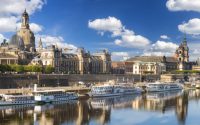 Panoramic view of Dresden's historical buildings along the Elbe River under a clear blue sky